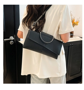 Vista posteriore di una modella con borsa a tracolla nera a effetto serpente e manico argento