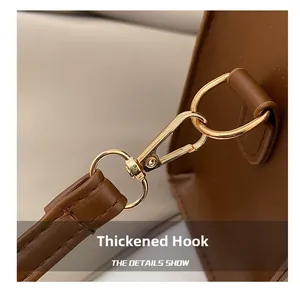 Close-up of durable golden metal swivel hook and brown leather strap on a shoulder bag
