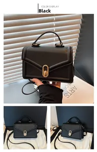 Détail d'un sac carré noir avec fermoir doré ovale et poignée en cuir élégante