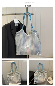Detail of blue gradient tote bag with lace flower patches and checkered woven handles