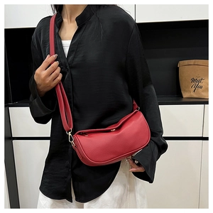 Close-up of red pebbled leather half-moon crossbody bag with gold hardware on model