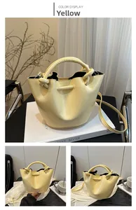 Detail of yellow bucket bag with a twisted handle and smooth vegan leather texture