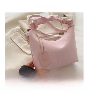 Détail du sac à main plissé rose clair avec pendentif et texture en cuir gaufré