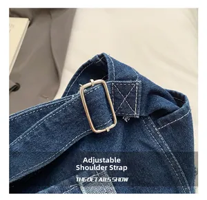 Close-up of adjustable shoulder strap with metal buckle on a navy denim bag