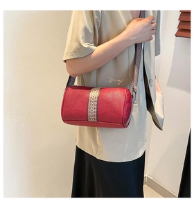 Detail of red pillow barrel bag with decorative webbing strap and lychee texture