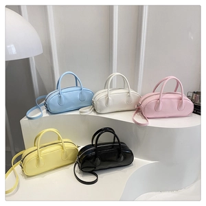 Minimalist glossy Boston handbags in five colors displayed on a modern curved stand