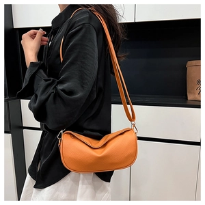 Detail view of orange lychee leather crossbody bag with pleated design and gold hooks