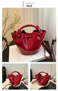 Detail of red glossy patent leather bucket bag with thick knotted handle and strap