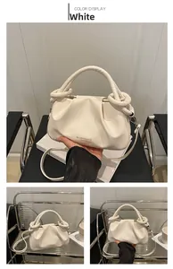 Dettaglio della borsa a pieghe in pelle color crema con manico a nodo e tracolla