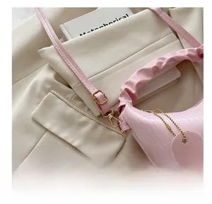 Détail du sac nuage rose montrant la poignée plissée et le fermoir doré sur fond beige