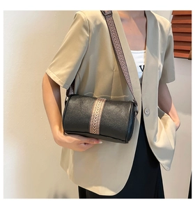 Detail shot of black textured leather cylinder bag with stylish geometric pattern strap
