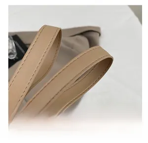 Detail of soft khaki faux leather tote bag handles with precise stitching and edge finishing
