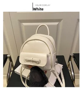 Close-up of a white mini backpack with a stylish bow decoration and magnetic flap pocket