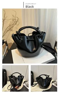 Detail of black glossy bucket bag featuring knot handle design and adjustable shoulder strap