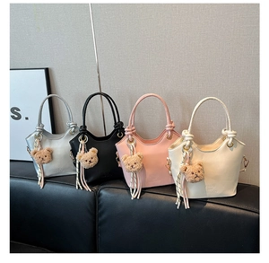 Serie di eleganti borse a secchiello in grigio, nero, rosa e crema con ciondoli a orsetto