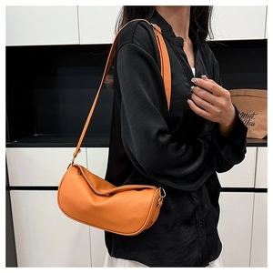 Close-up of bright orange lychee grain leather dumpling bag on a female model