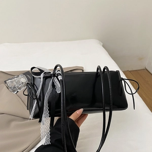 Sac sous le bras noir brillant avec nœud en dentelle blanche et cordons latéraux