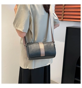 Detail of black pebbled leather boston bag with a patterned woven wide shoulder strap