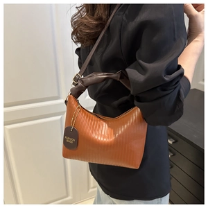Vue détaillée du sac plissé orange avec poignée froncée marron foncé et étiquette en cuir