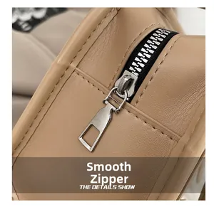 Detail of smooth silver zipper and stitching on khaki leather shoulder bag