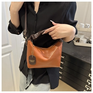 Détail du sac à main plissé orange-brun avec étiquette et poignée marron foncé froncée