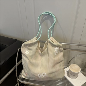 Floral embroidery beige tote bag with woven handles on a stylish metal chair