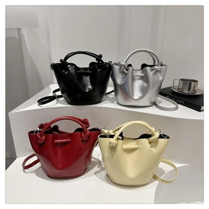 Minimalist bucket bags in black, silver, red, and yellow on modern display stands