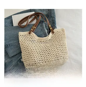 Dettaglio borsa tote intrecciata crema con manico in pelle marrone su denim blu