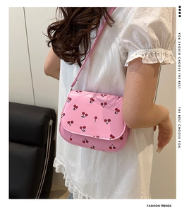 Pink cherry print crossbody bag in glossy finish shown from a side view on a model
