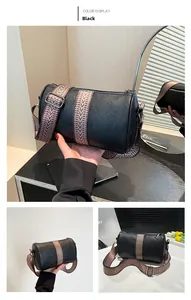 Detail of black lychee leather cylinder bag with wide patterned shoulder strap