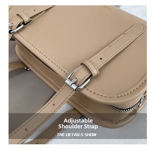 Detail of adjustable shoulder strap with silver buckle on chic beige crossbody bag