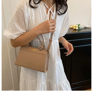 Detail of beige crocodile pattern tote bag with gold lettering and knotted handle