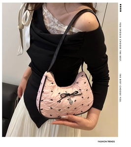 Pink hobo bag with black bows and heart pendant worn by model for style detail