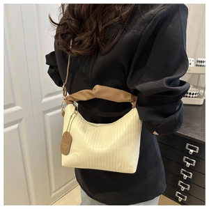 Détail d'un sac plissé beige avec poignée nuage marron et étiquette de mode ronde