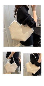 Detail of woven straw tote bag with white leather straps and V-shaped edge design