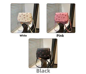Three small saddle bags in white, pink, and black featuring red cherry prints