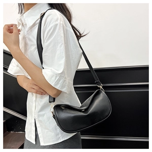 Detail of black pebbled leather dumpling bag with adjustable strap and gold buckle