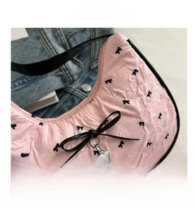 Dettaglio borsa rosa stropicciata con fiocchi neri e ciondolo a cuore in argento