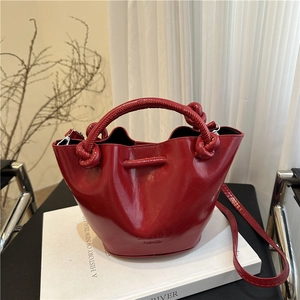 Retro burgundy patent leather bucket bag with twist handle and detachable strap on white book