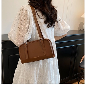 Brown leather underarm bag with silver buckles shown on model in white lace dress
