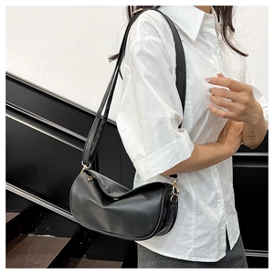 Detail of black lychee texture crescent bag with adjustable strap and gold metal buckle