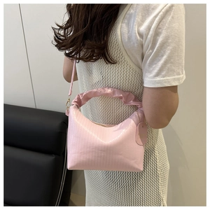 Vue détaillée du sac à main plissé rose avec poignée anneau et motif texturé vertical