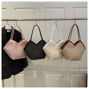 Multiple woven large capacity tote bags in pink, black, white, and brown hanging on a rack