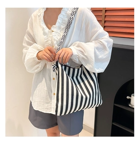 Detail der schwarz-weiß gestreiften Canvas-Tasche mit geometrisch gewebtem Schultergurt am Model