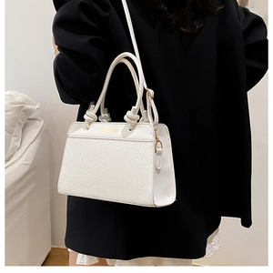 Detail of white crocodile texture handbag with golden Fashion Bag lettering on black blazer