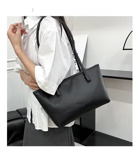 Close-up of minimalist black leather tote bag with smooth matte finish and slim shoulder strap