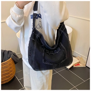 Detail of black denim tote bag with white contrast stitching and distressed frayed edges