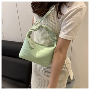 Détail du sac seau vert menthe avec texture plissée verticale et étiquette latérale
