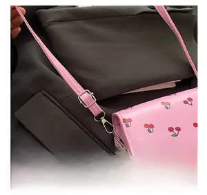 Detail of pink cherry crossbody bag featuring adjustable shoulder strap and metal hardware