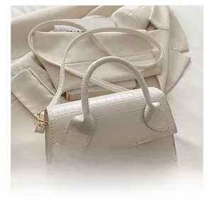 Macro view of white crocodile pattern PU handbag with gold logo and elegant details